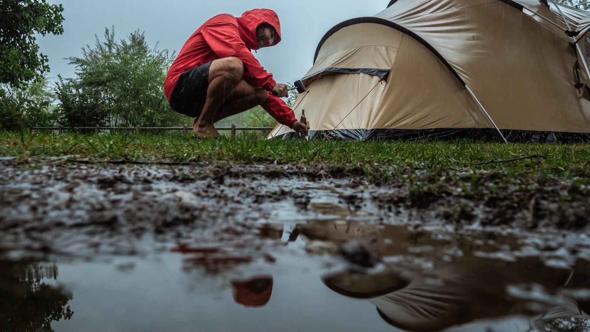 man camping fixing tent rainy 909477266